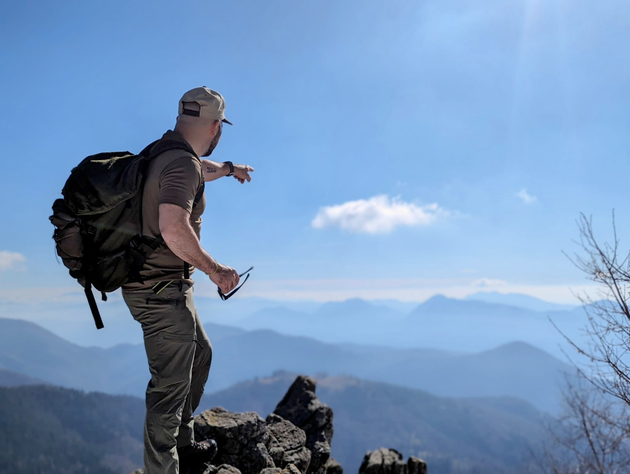 Daniele Mele wijst vanaf een bergtop naar de horizon, tijdens een Cima del BenEssere trail in de Italiaanse Alpen